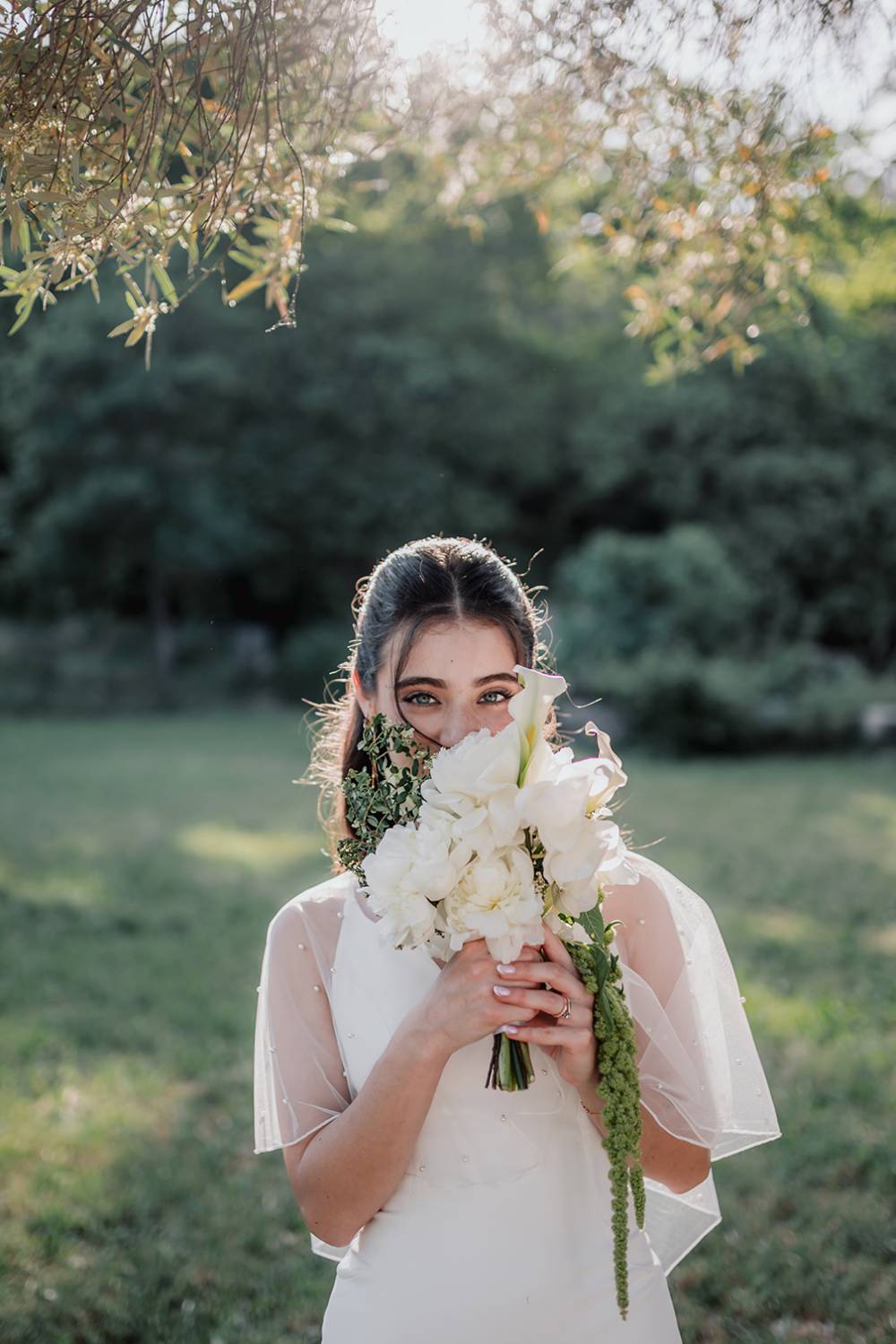 Jeune mariée derrière un bouquet de fleurs