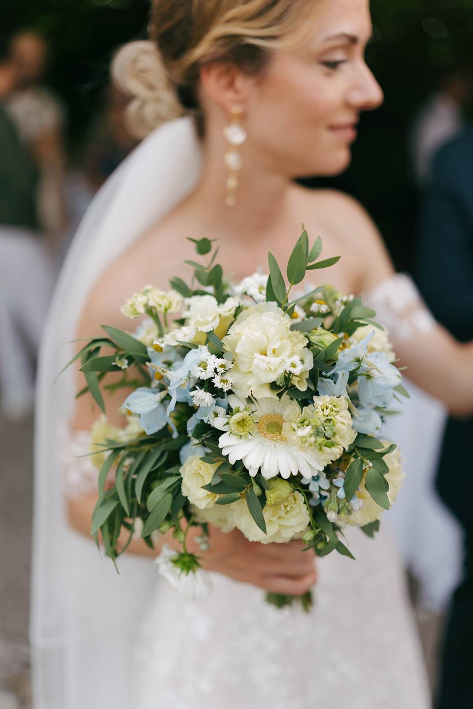Mariée de profil tenant un bouquet